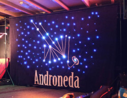 Podiumdecoratie met bandnaam en logo, en ledlampjes die via Arduino met verschillende effecten zijn geprogrammeerd. Hier kun je hem in actie zien: https://www.youtube.com/watch?v=hVjScCpMOsY Achtergronddoek met lichteffecten