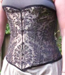 Corset with cups and boning, front closure, and laces in the back. Corset