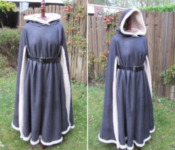 Mantel met zij-openingen en capuchon, gemaakt van grijze stof met dikke witte nepbont voering. Warme mantel